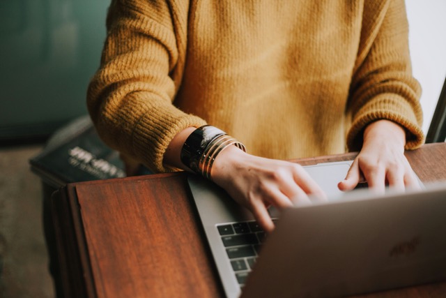 A woman's hands at a laptop keyboard, editing photos